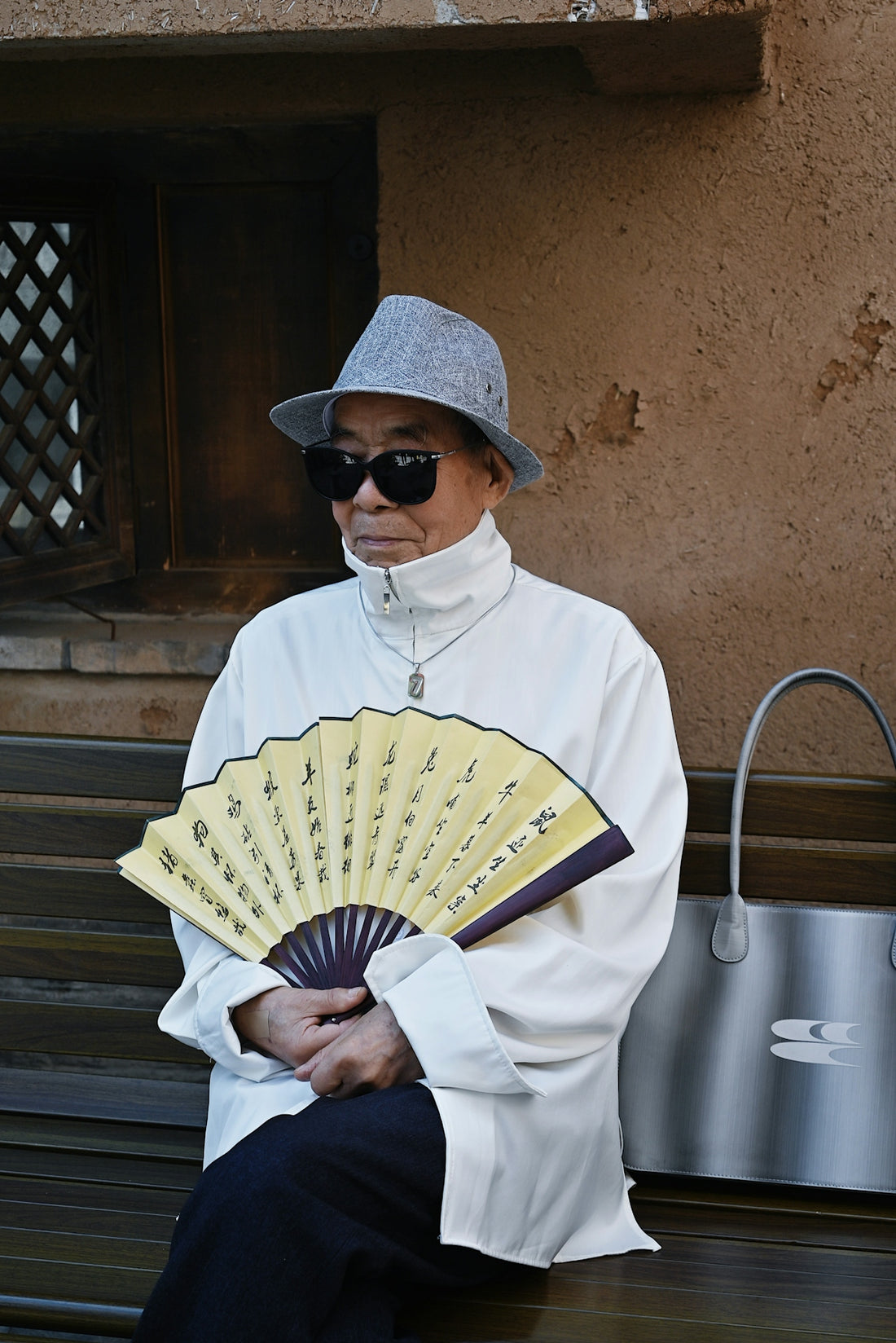 a man sitting on a bench holding a fan