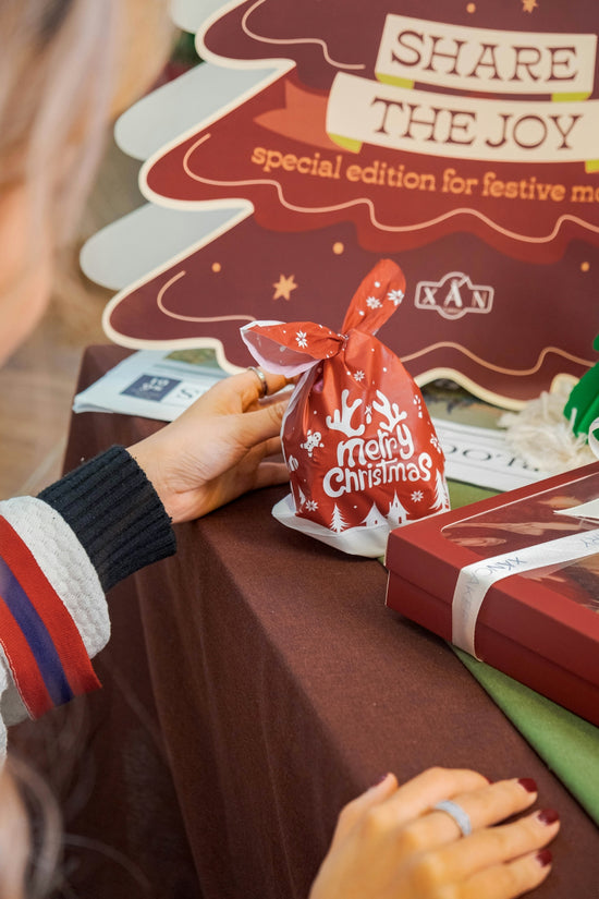 a woman is putting a bag of christmas candy on a table