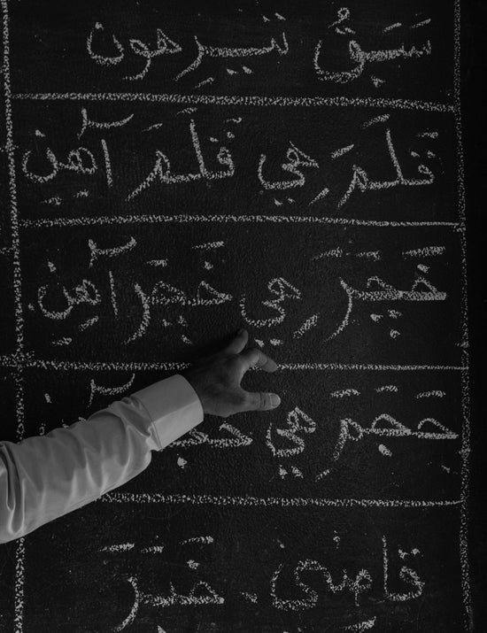 a young boy is writing on a blackboard