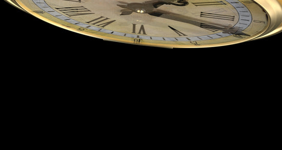 A gold clock with roman numerals on a black background