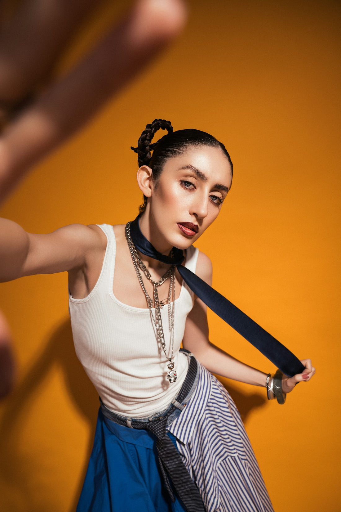 Woman poses confidently against a bright orange background.