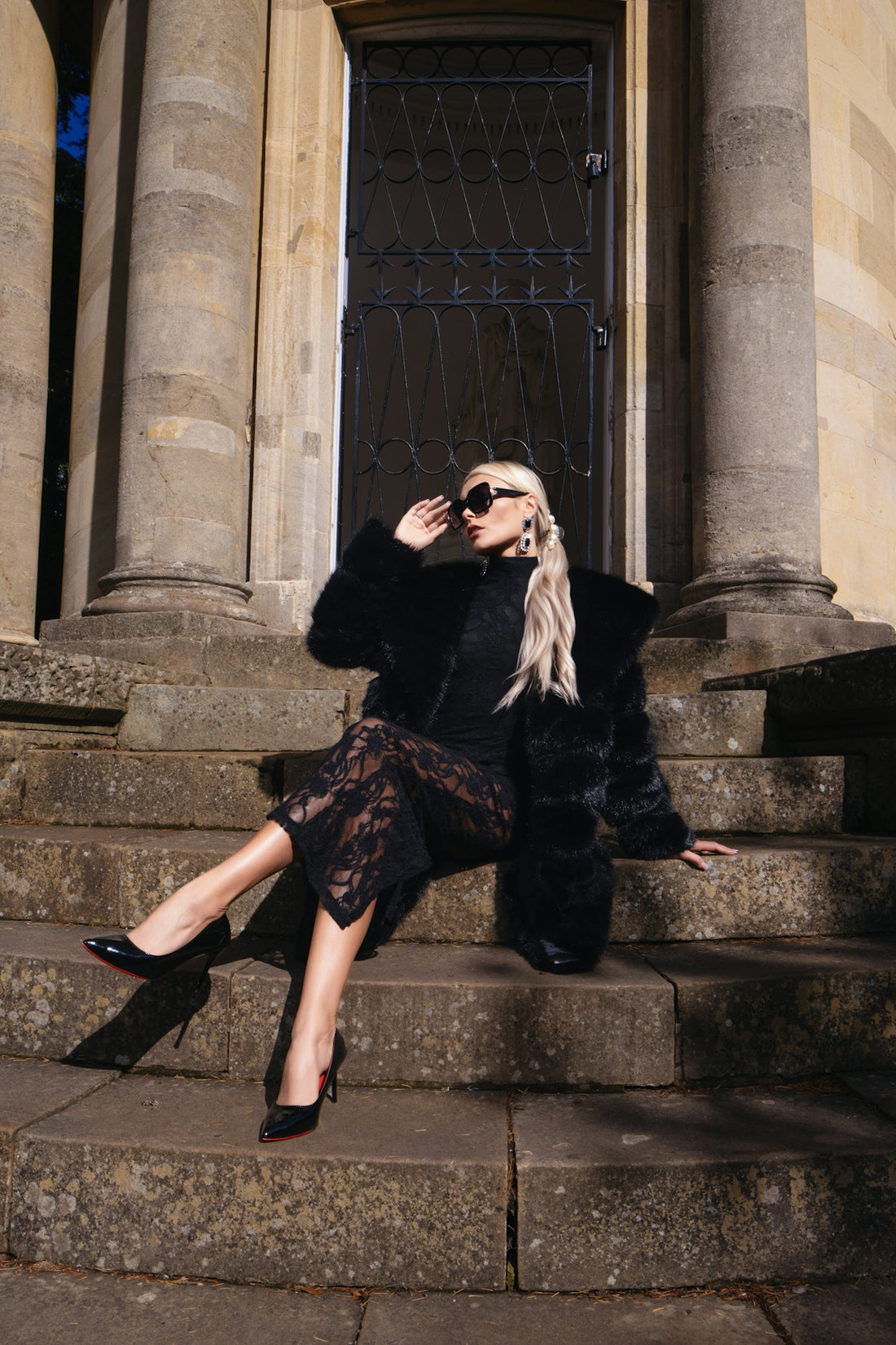 Woman in fur coat and lace dress sitting on steps