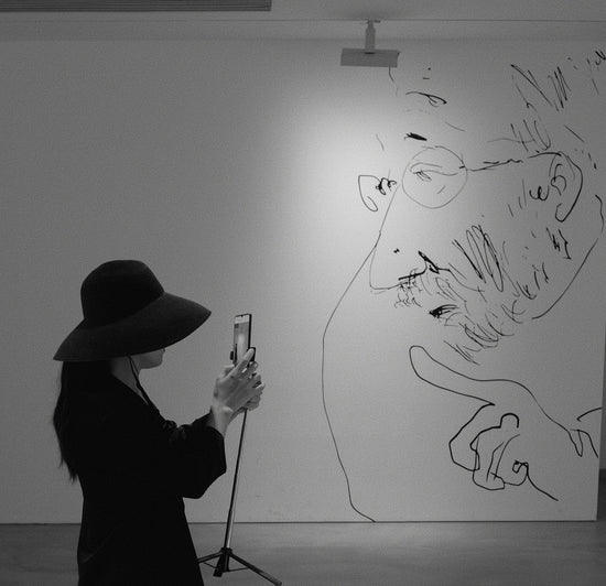 Woman photographs large sketch of a man's face
