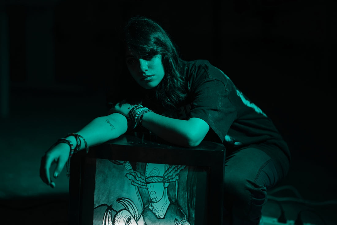 Young woman in dark room with teal lighting.