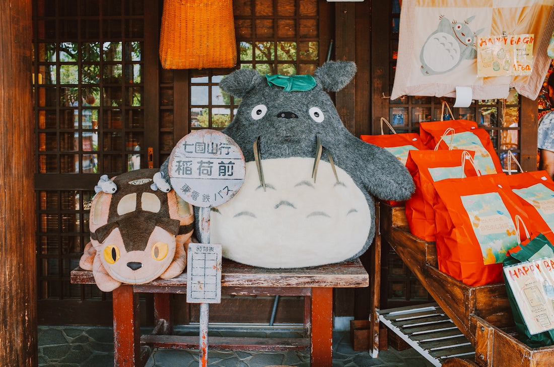Totoro plush toys and merchandise displayed outdoors.