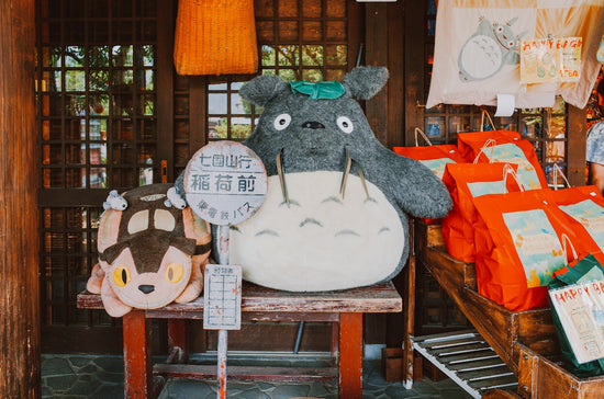 Totoro plush toys and merchandise displayed outdoors.