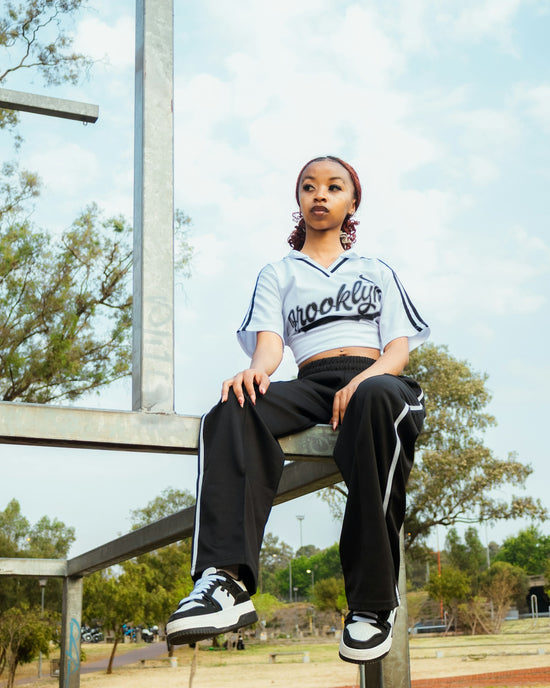 Young woman in athletic wear sitting on metal structure.