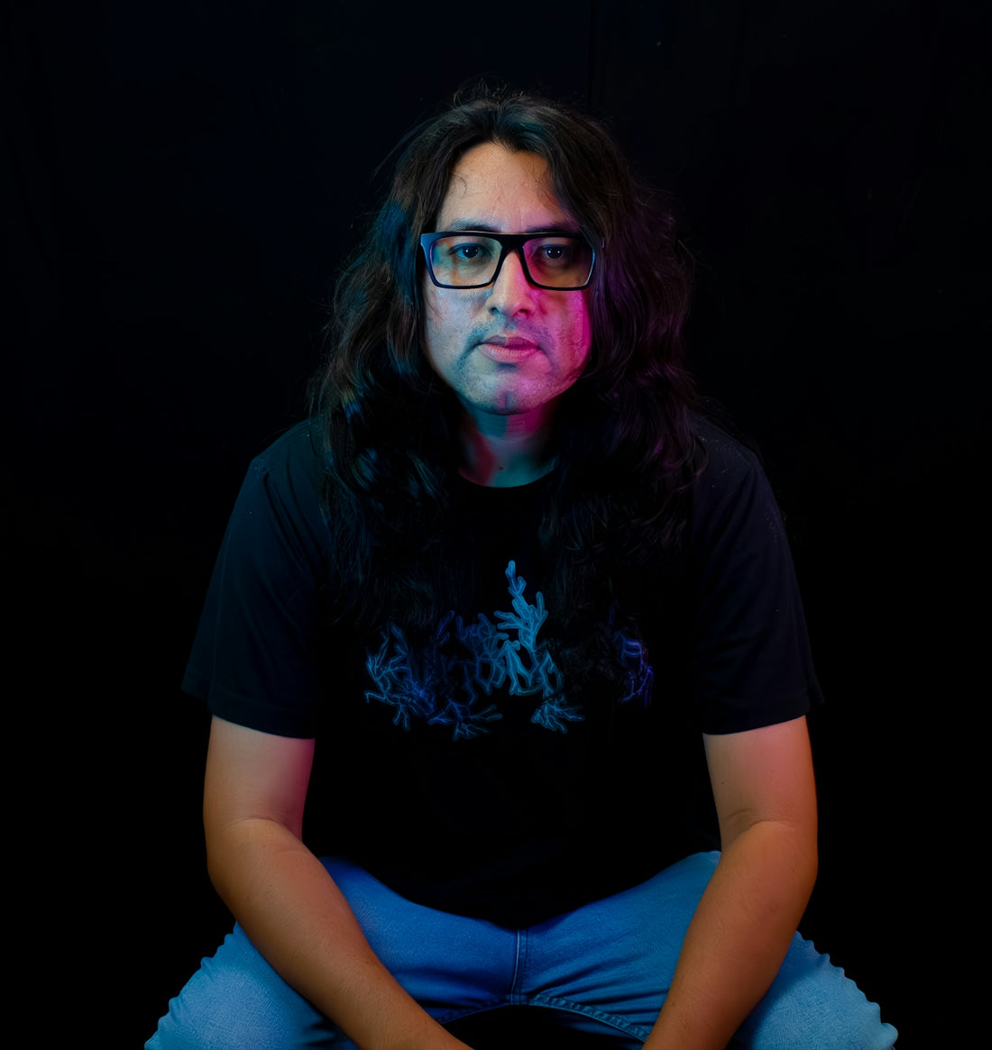 Man with long hair and glasses wearing a t-shirt