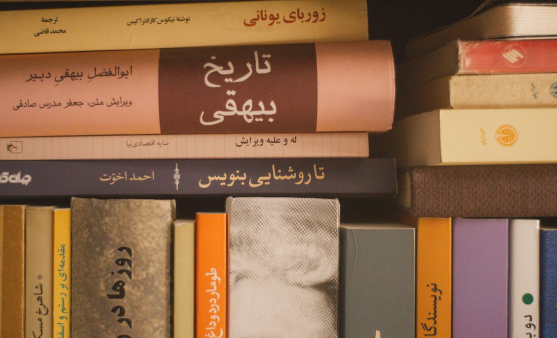 A close-up of stacked books with persian titles.