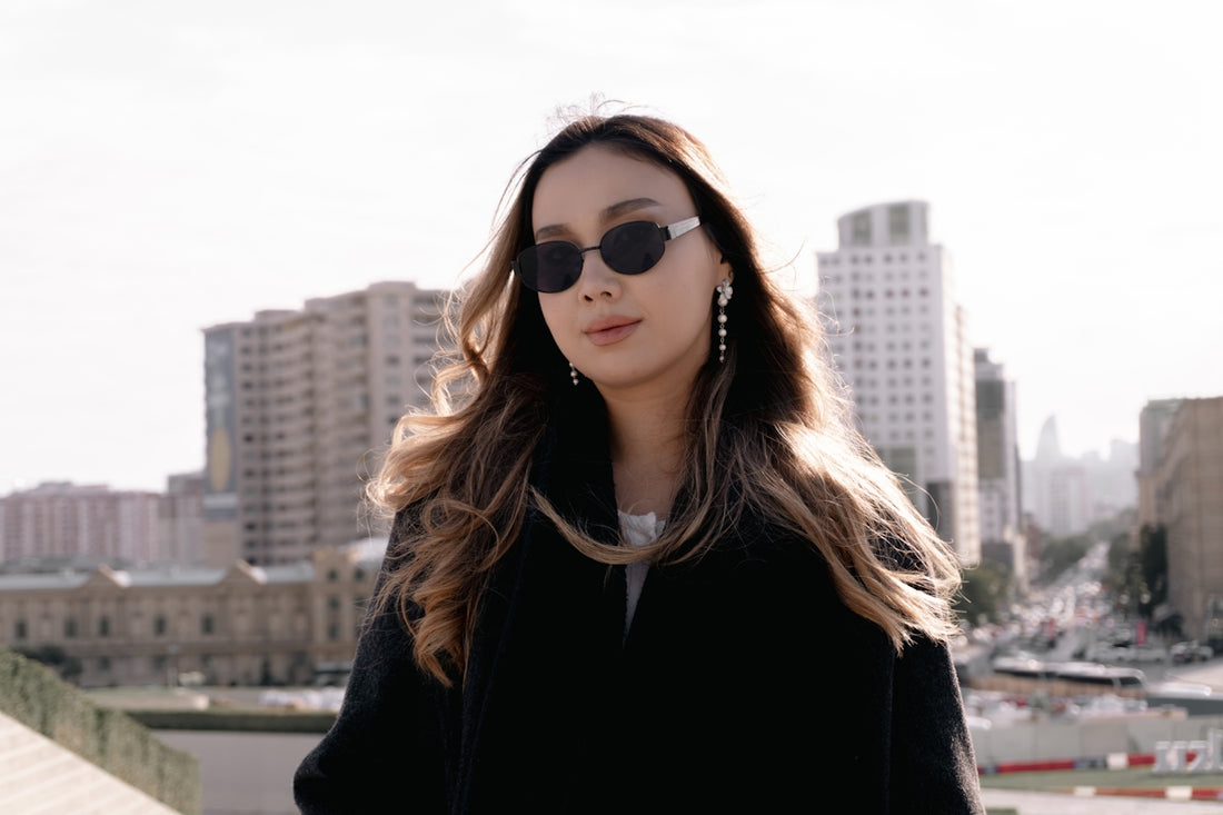 Stylish woman wearing sunglasses with city buildings behind.