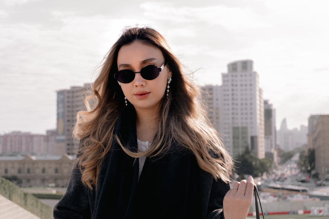 Woman wearing sunglasses and a black coat outdoors.