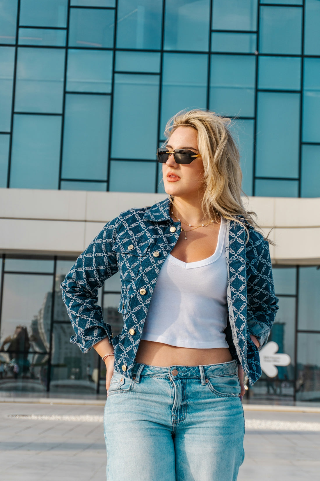 Woman in denim jacket and jeans standing outdoors.