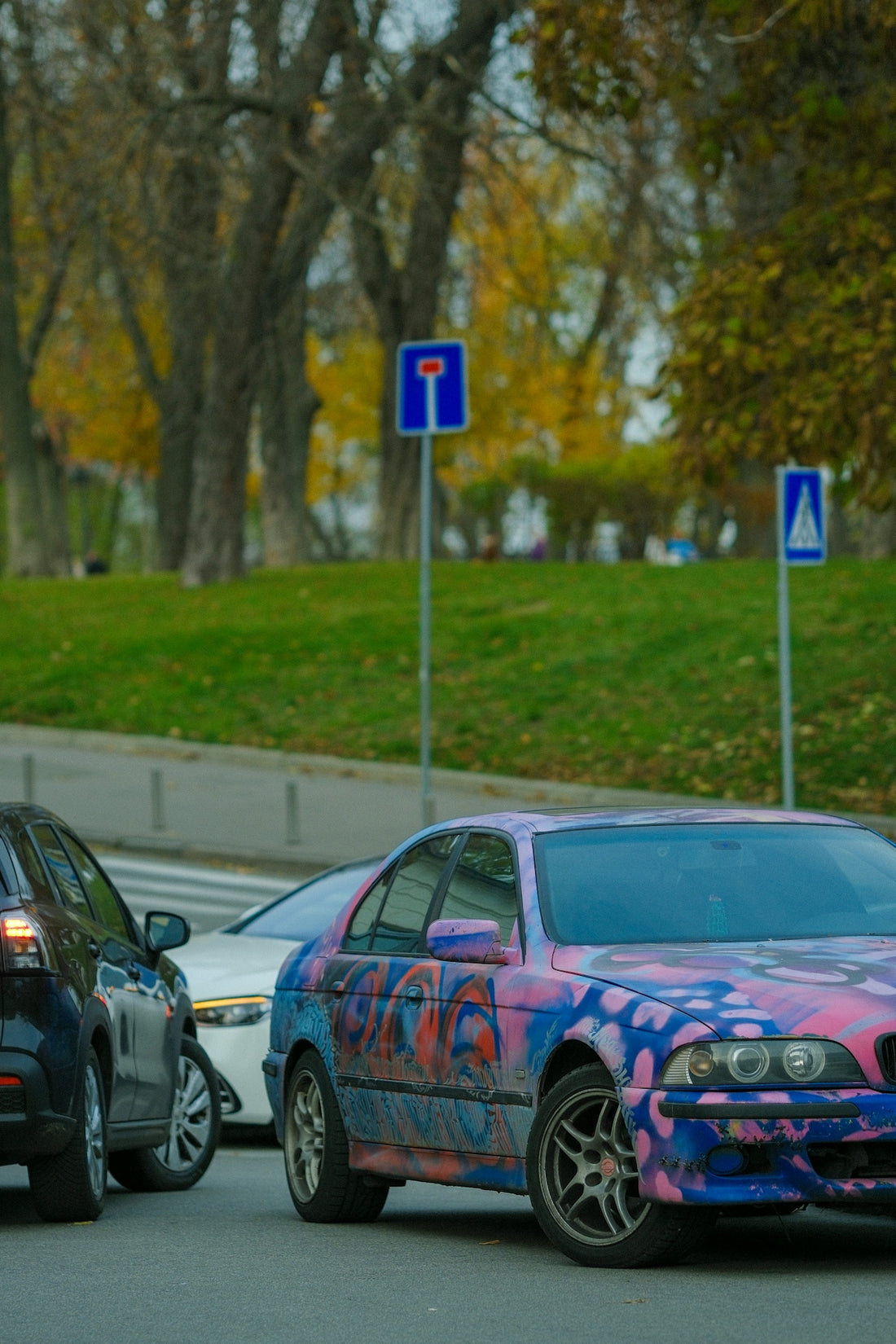 Cars with graffiti in traffic on a street.