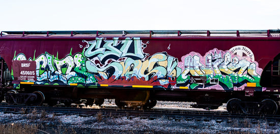Graffiti art covers a maroon train car