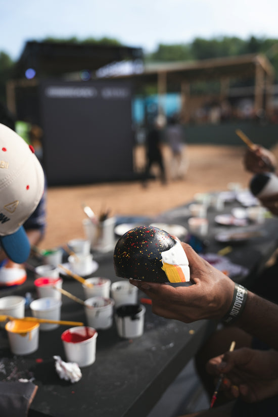 Person holding a painted helmet with colorful speckles.