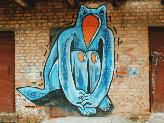 Blue creature graffiti on a brick wall