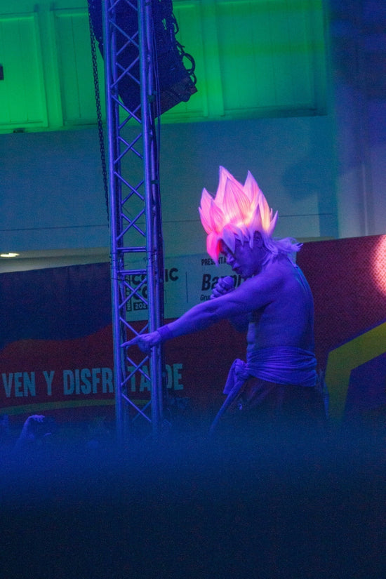 Man dressed as goku with glowing hair performs on stage.