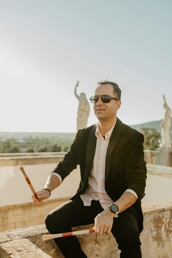 Man in suit holding drumsticks outdoors