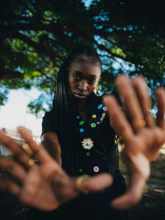 Young black woman with braids holding hands up