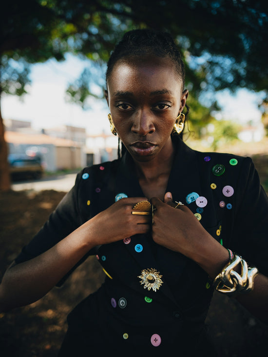 A woman in a black blazer with colorful buttons.