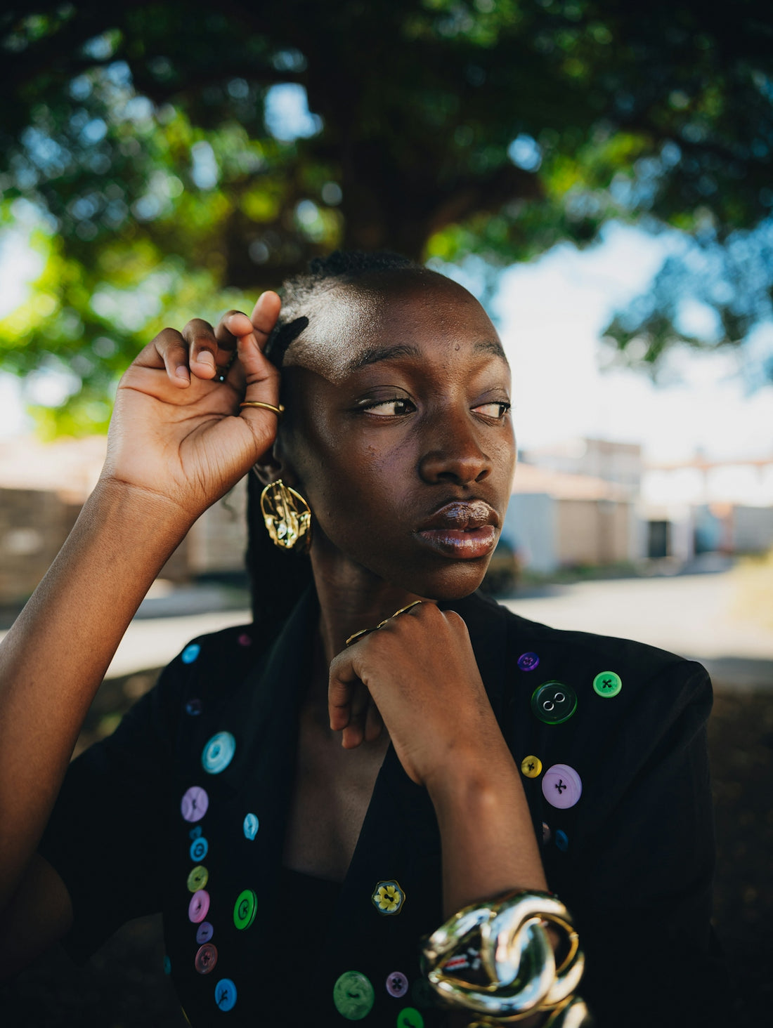 Woman with colorful buttons on blazer adjusts her hair.