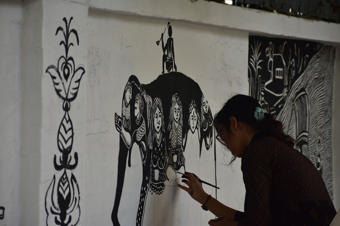 Artist paints a mural on a white wall.