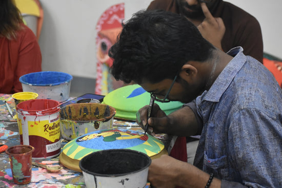 Man painting a colorful object with a brush.
