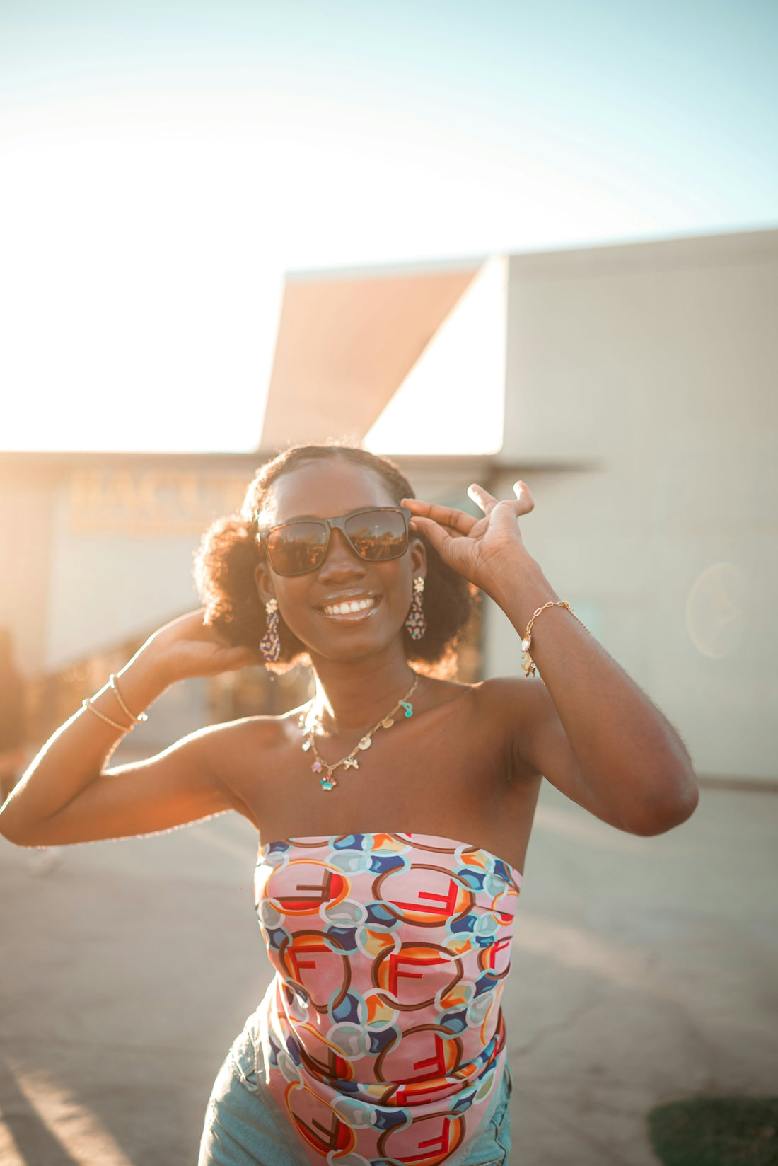 Young woman in sunglasses smiles brightly outdoors.
