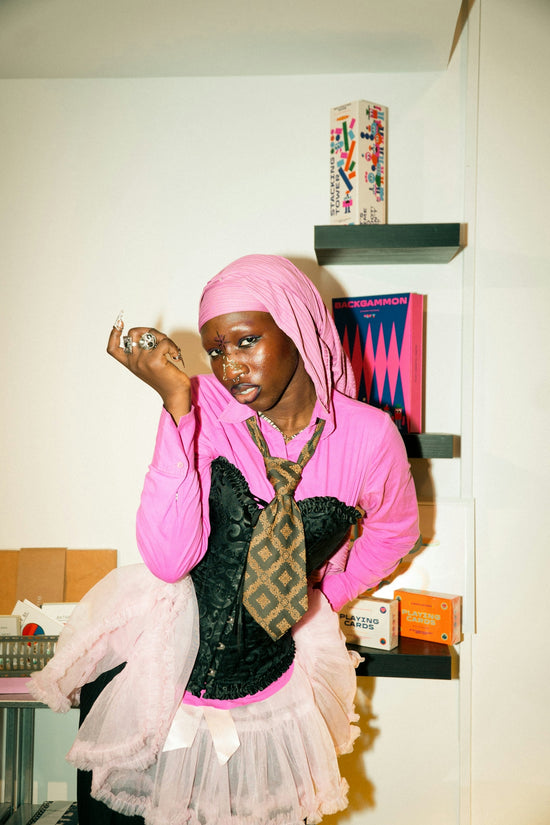 Person in pink headscarf, corset, and tutu.