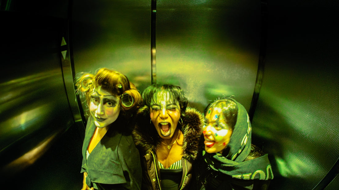 Three women with dramatic makeup in a dark space.