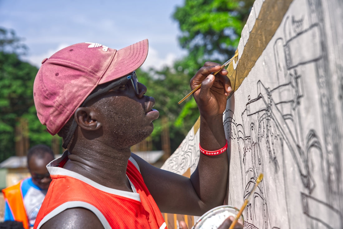 Artist painting a mural outdoors with a brush