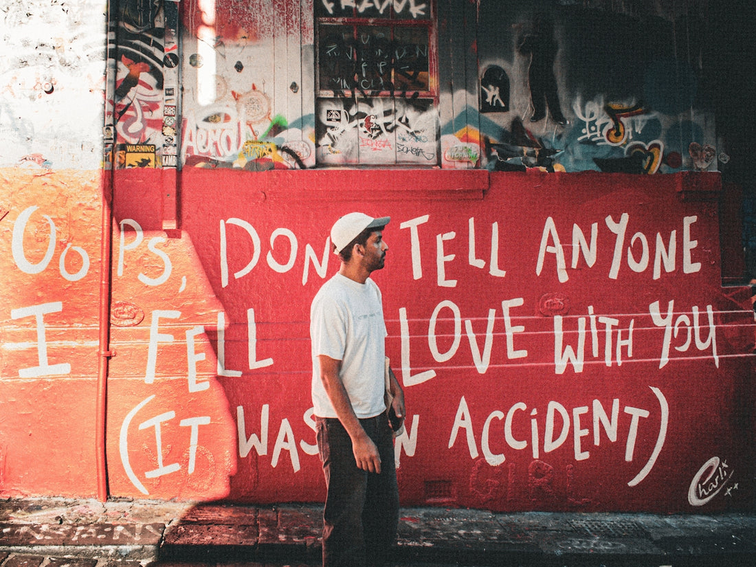 Man stands against red wall with graffiti.