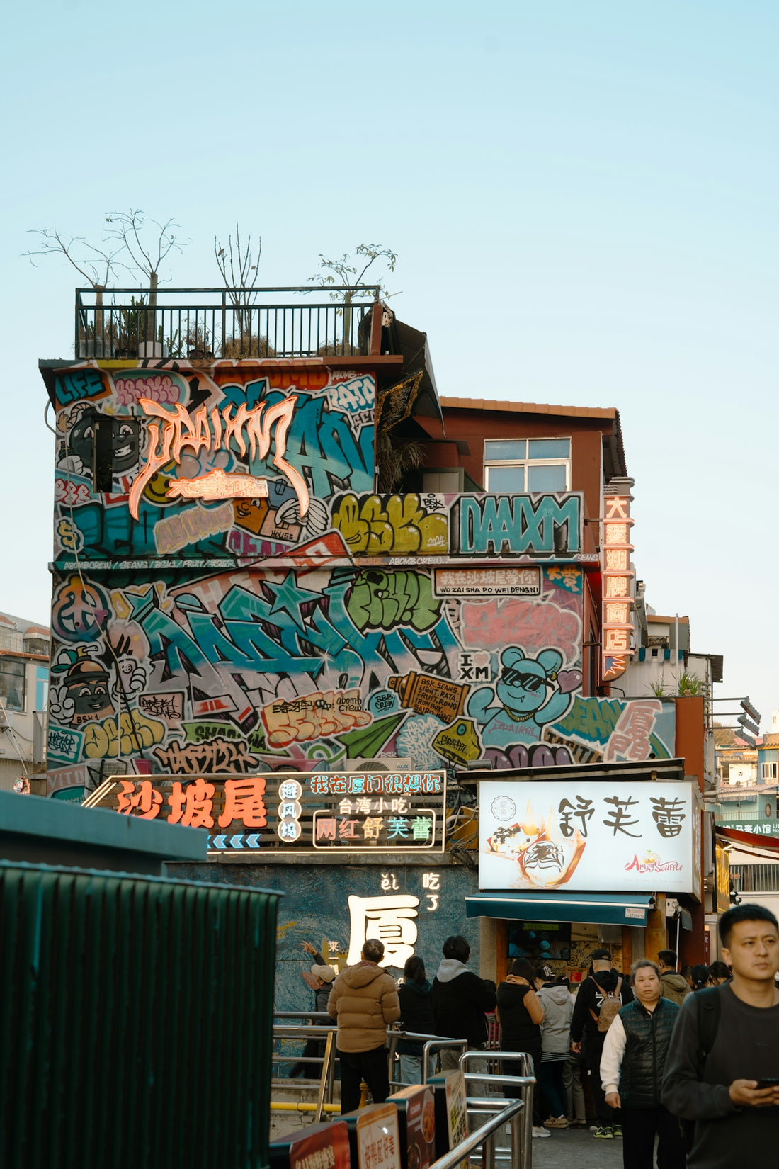 Building covered in colorful graffiti with people on street.