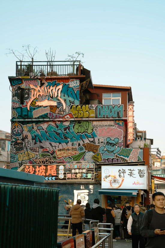 Building covered in colorful graffiti with people on street.