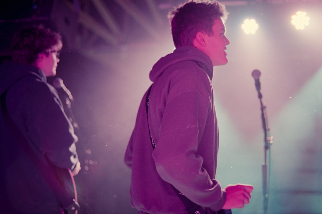 Man singing into microphone under stage lights