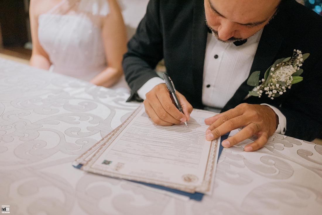 Groom signing marriage certificate with bride beside him