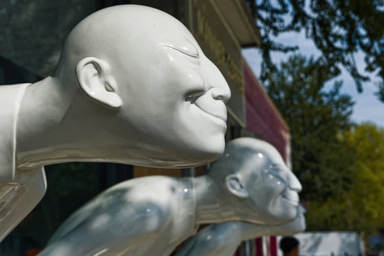Three white bald figures with smiling faces in a row.