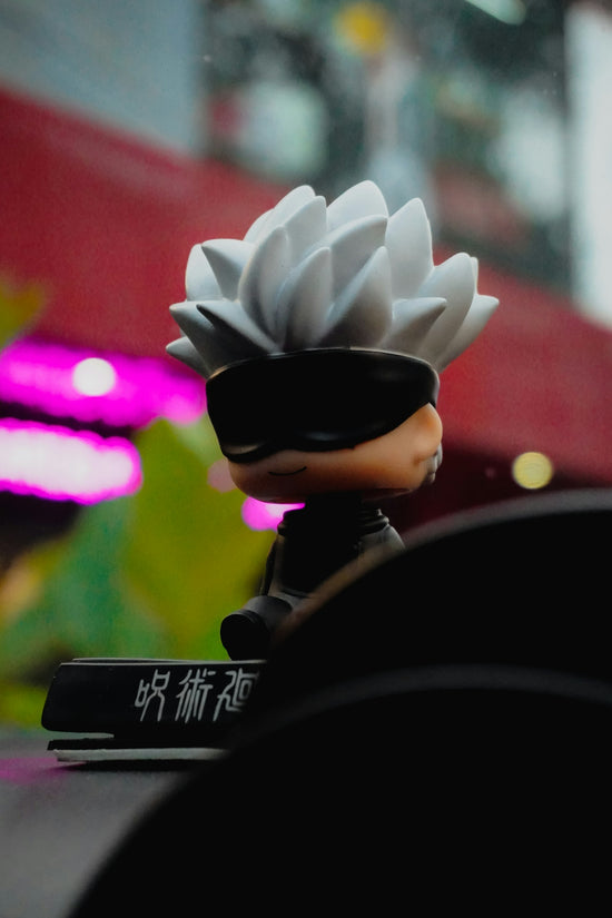 Anime figure with white spiky hair and black blindfold.