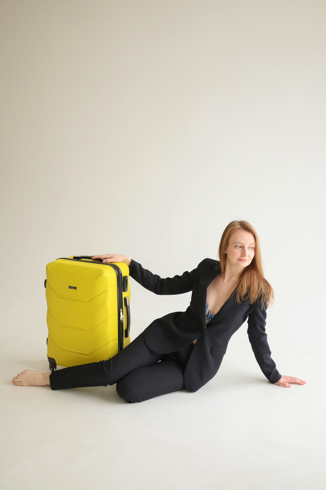 Woman in a suit with a yellow suitcase