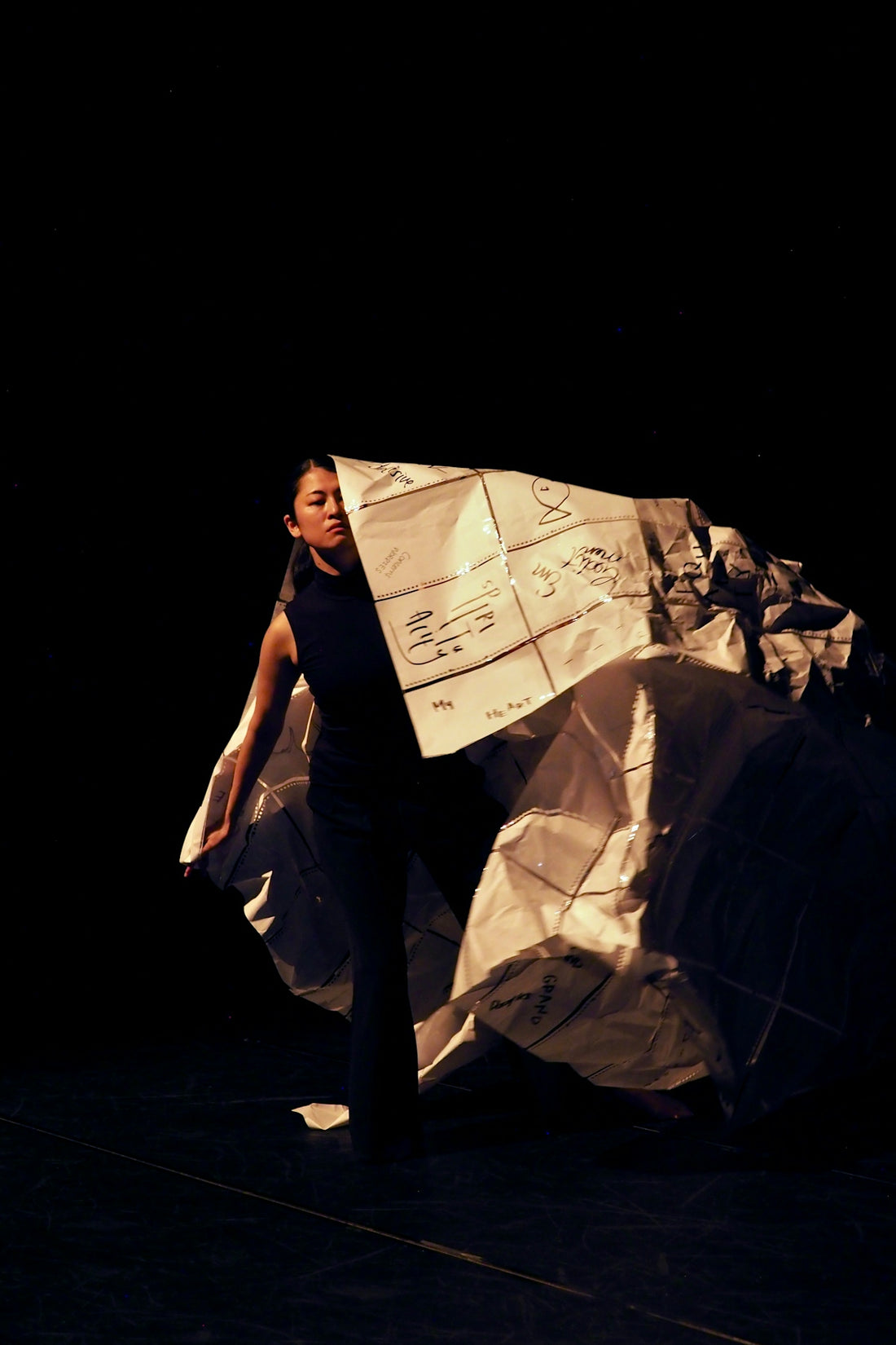 Woman holding a large, crumpled paper structure