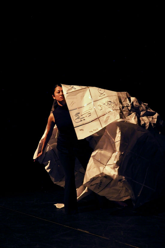 Woman holding a large, crumpled paper structure