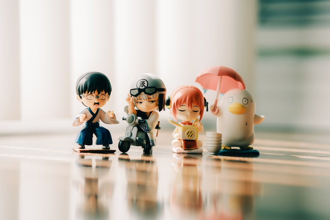 Four small figurines stand together on a reflective surface.