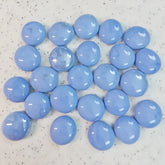 Glossy light blue round glass marbles on speckled white surface