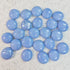 Glossy light blue round glass marbles on speckled white surface