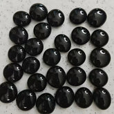 Array of polished black obsidian stones on a speckled white surface