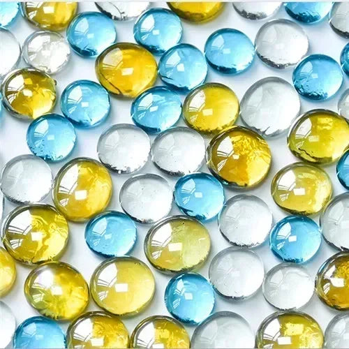 Close-up of small round glass beads in blue, yellow, and clear colors on a white surface