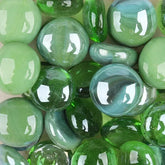 Close-up of shiny green and blue glass pebbles with smooth rounded shapes