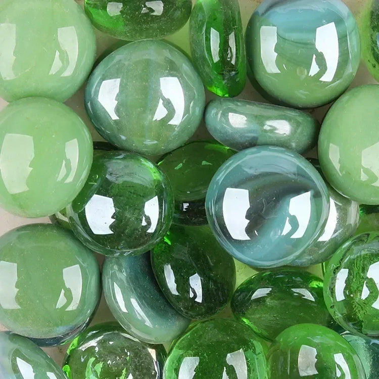Close-up of shiny green and blue glass pebbles with smooth rounded shapes
