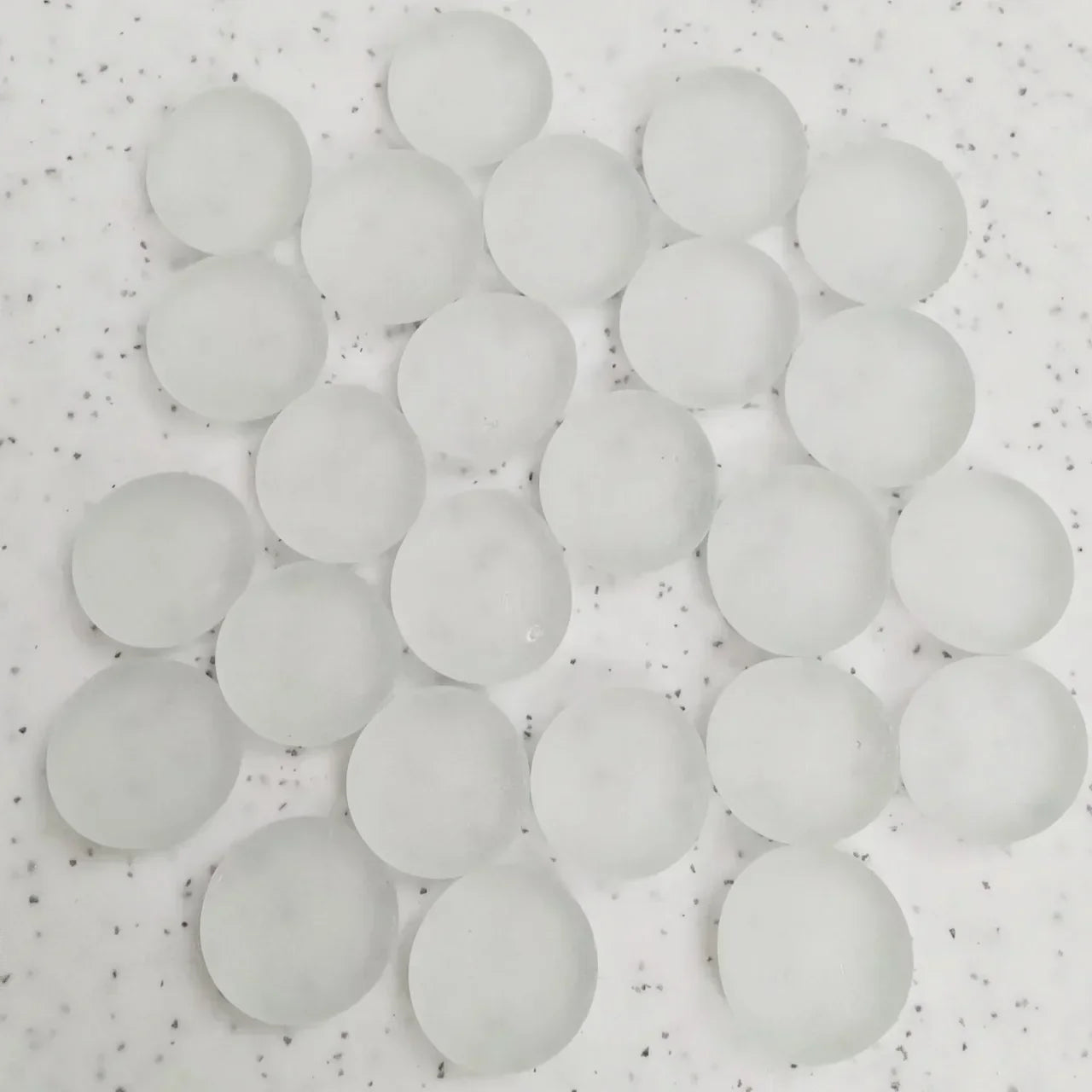 Cluster of translucent white silica gel desiccant beads on speckled surface