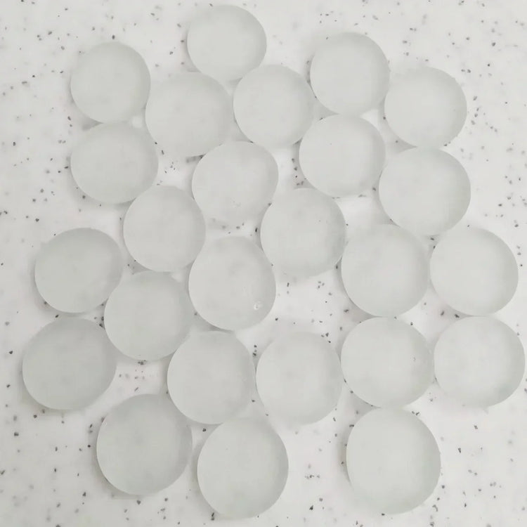 Cluster of translucent white silica gel desiccant beads on speckled surface